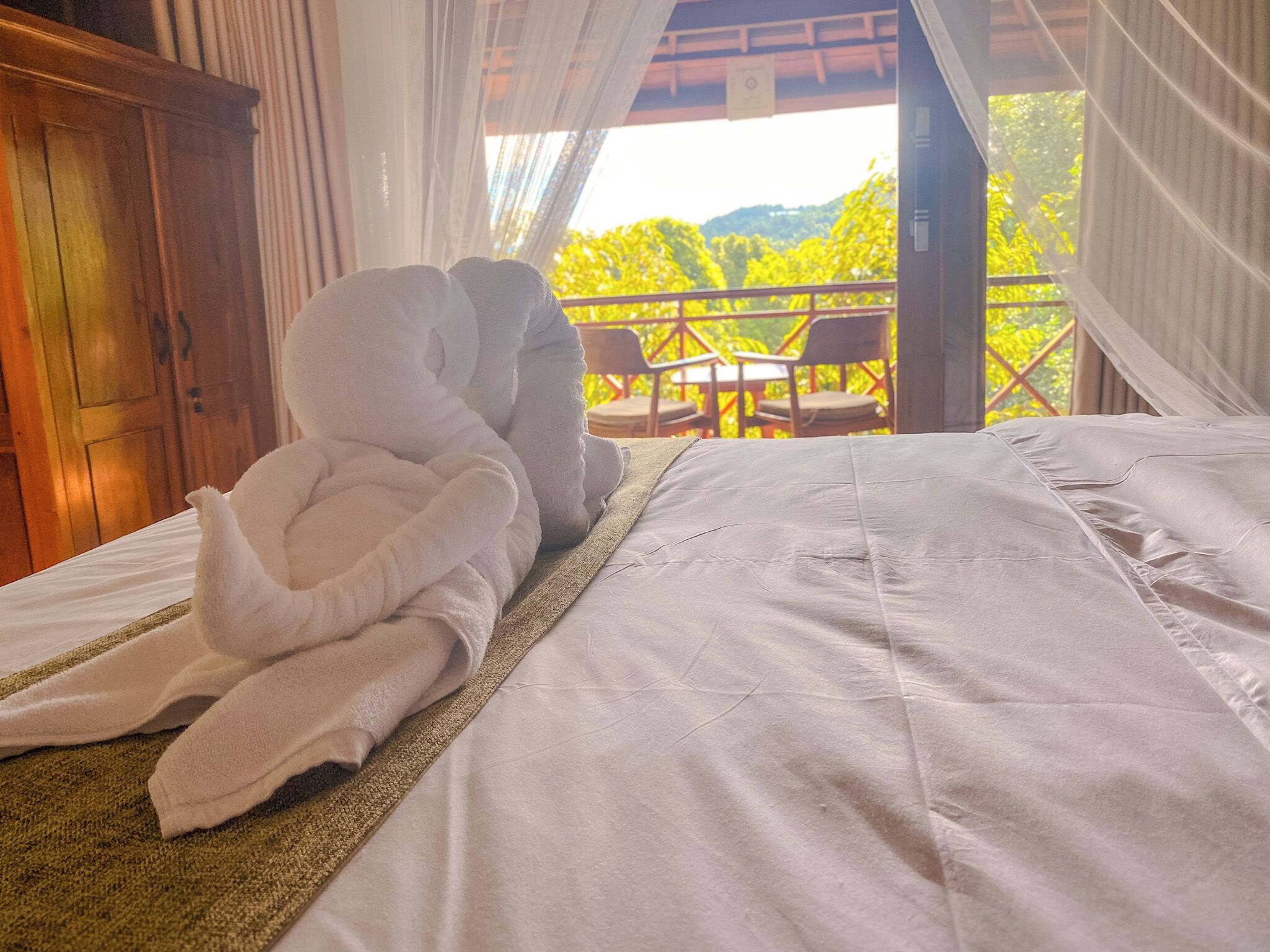 Ein Schlafzimmer mit Bett, einem Holzschrank und einem Balkon mit Tisch und Stühlen.