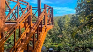 A wooden staircase leading to a covered area with a view of a lush green landscape and a clear blue sky. - Wimala Farm House (Munduk)