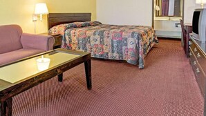 A hotel room with a bed, a sofa, a desk, a TV, and a mirror. - Guest Inn Lebanon (Lebanon)