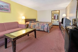 A hotel room with a bed, a sofa, a desk, a television, and a mirror. - Guest Inn Lebanon (Lebanon)