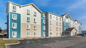 Ein mehrstöckiges Hotel mit Parkplatz vor der Tür.