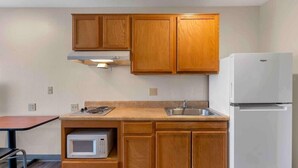 Eine kleine Küche mit Holzausstattung, einer Mikrowelle, einem Spülbecken und einem weißen Kühlschrank.