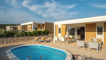 A modern pool area with a clear blue pool, lounge chairs, and a stone wall.