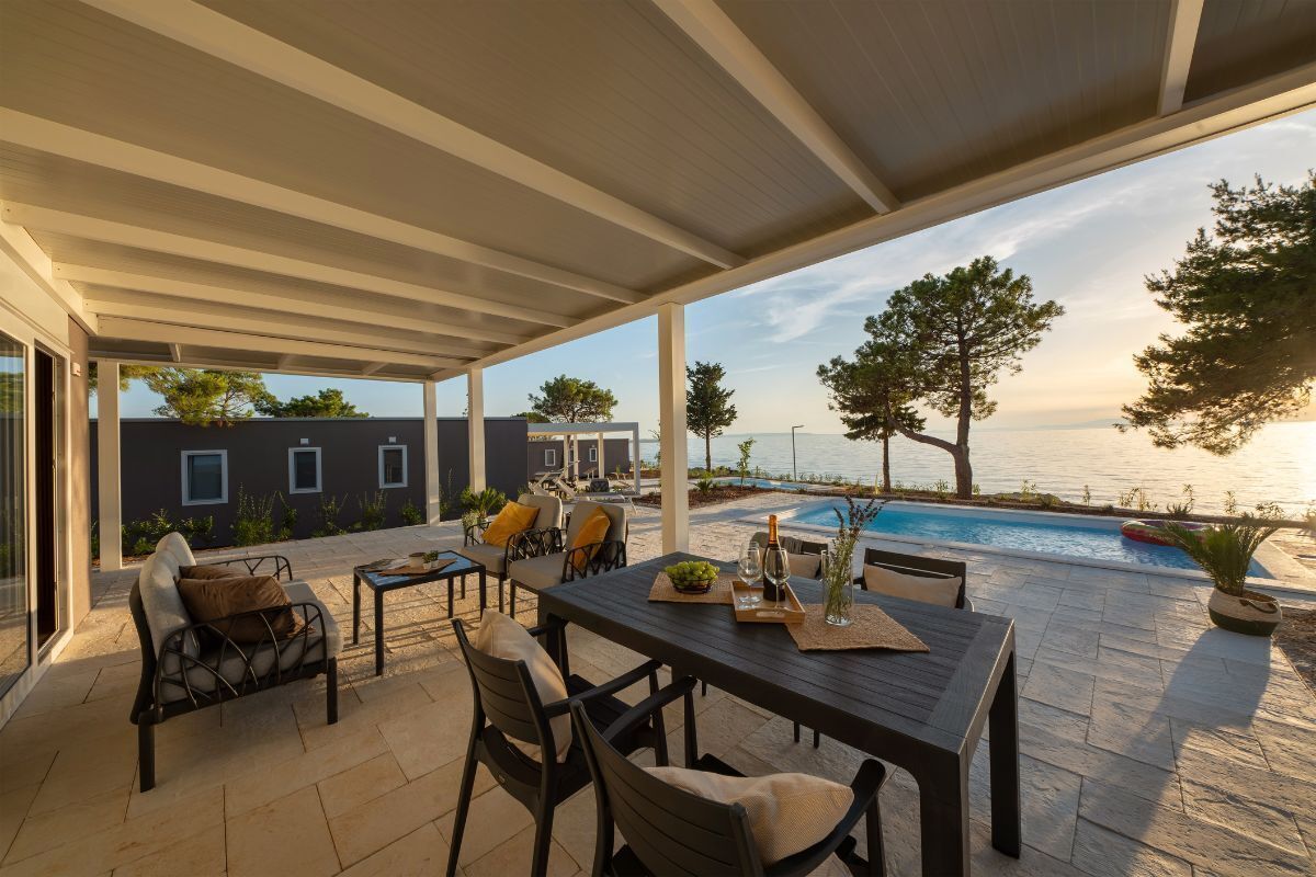 An outdoor patio with a pool, seating, and a view of the sea.