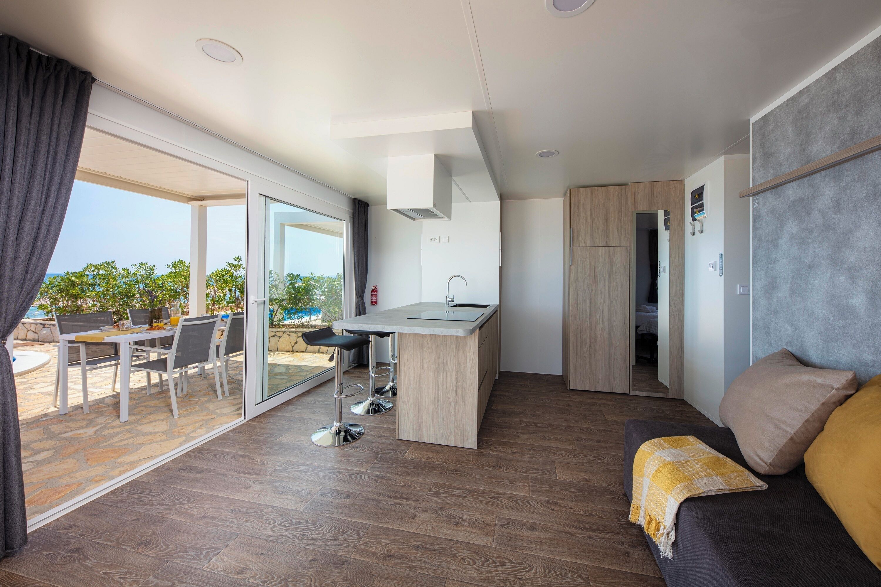 A modern apartment with a kitchen, dining area, and a balcony with a view.
