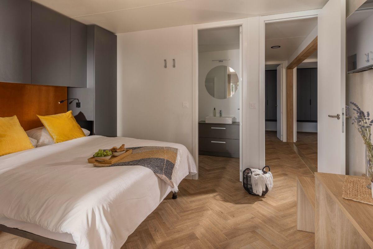 A modern bedroom with a bed, bedside table, and a mirror.