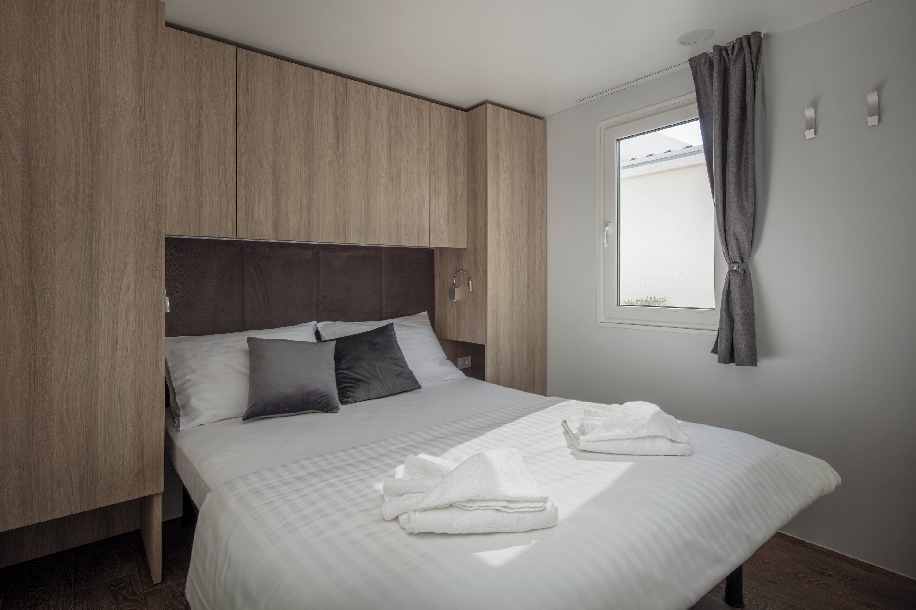Une chambre moderne avec un grand lit, une armoire en bois et une fenêtre avec des rideaux.