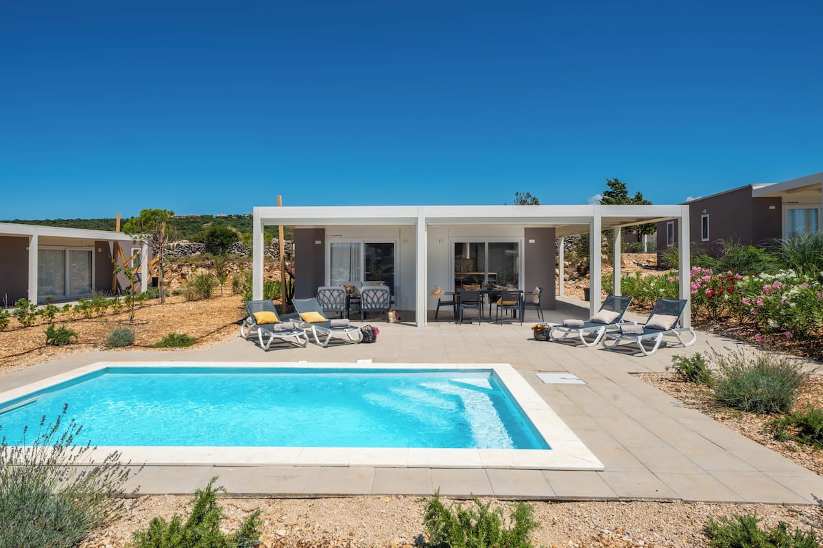 Uma villa moderna com piscina, área de estar ao ar livre e alpendre coberto.