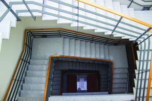 A modern staircase with a geometric design, featuring a central open area with a window and a wooden handrail.