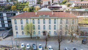 Un edificio grande con techo de tejas rojas y varias ventanas. Hay varios coches estacionados adelante.