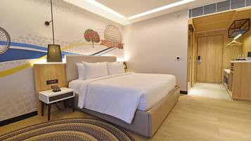 A modern hotel room with a large bed, bedside table, and a decorative wall mural.