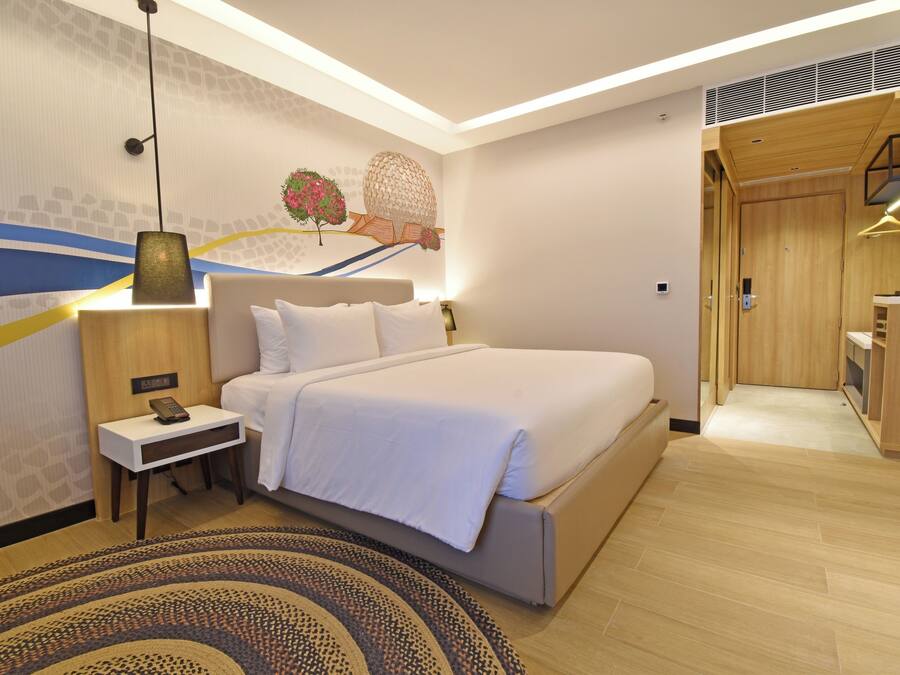 A modern hotel room with a large bed, bedside table, and a decorative wall mural.