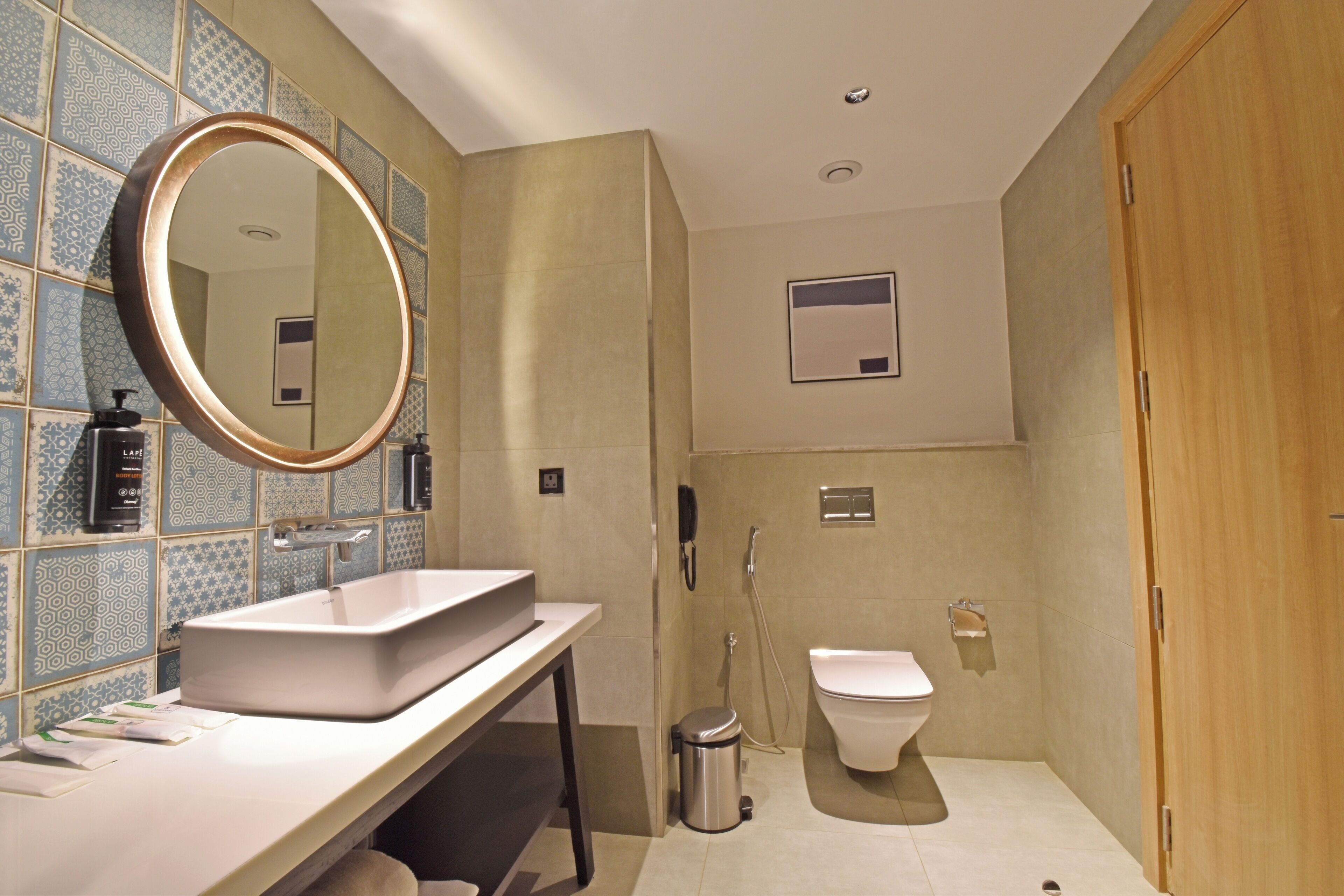Un baño moderno con un espejo grande, un lavabo, un inodoro y una ducha.