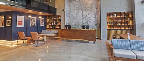A modern lobby with a reception desk, seating area, and a large wall mural.