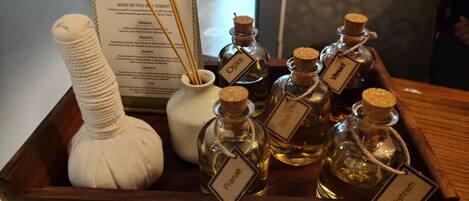 A wooden tray with several bottles of essential oils, a white ceramic diffuser, and a menu card.