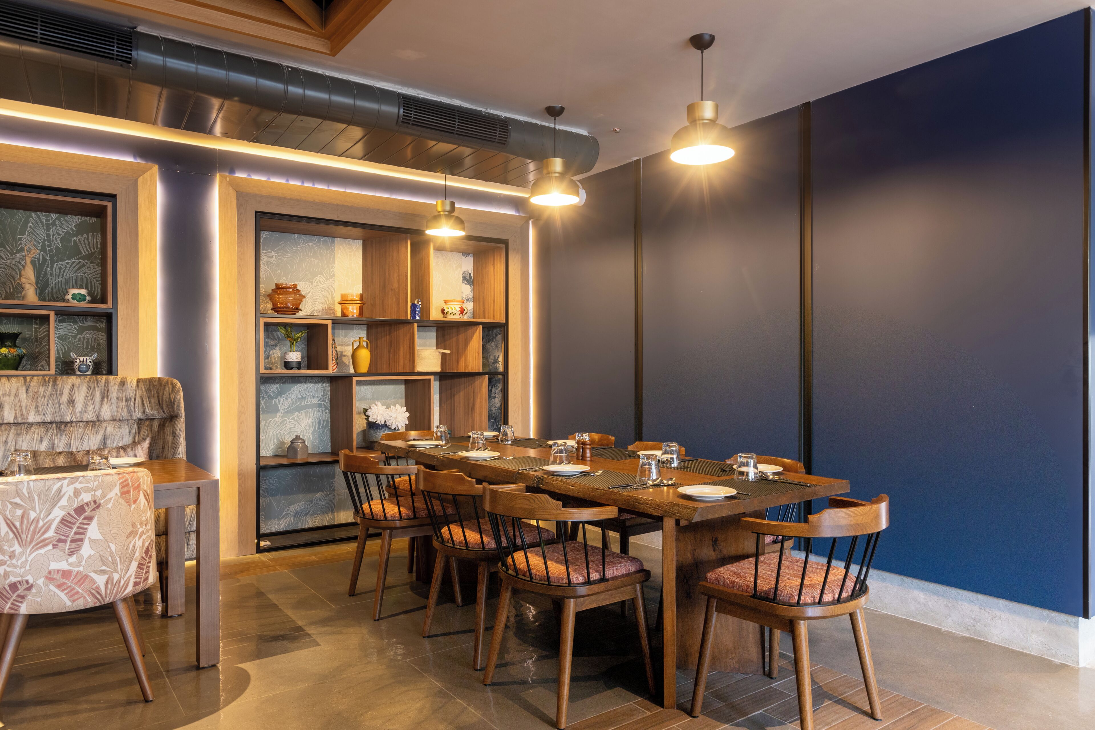 A dining area with a long wooden table, multiple chairs, and pendant lighting.