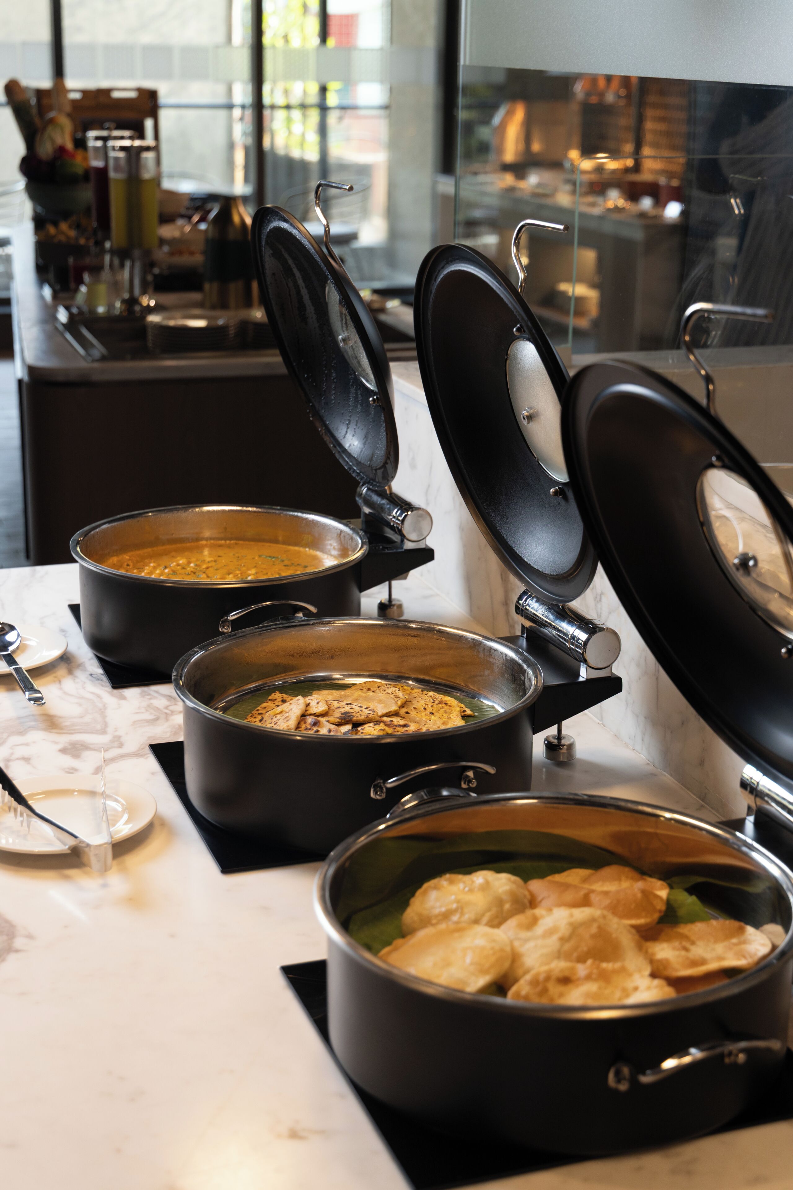 A kitchen area with three pots on the counter, one with its lid open.