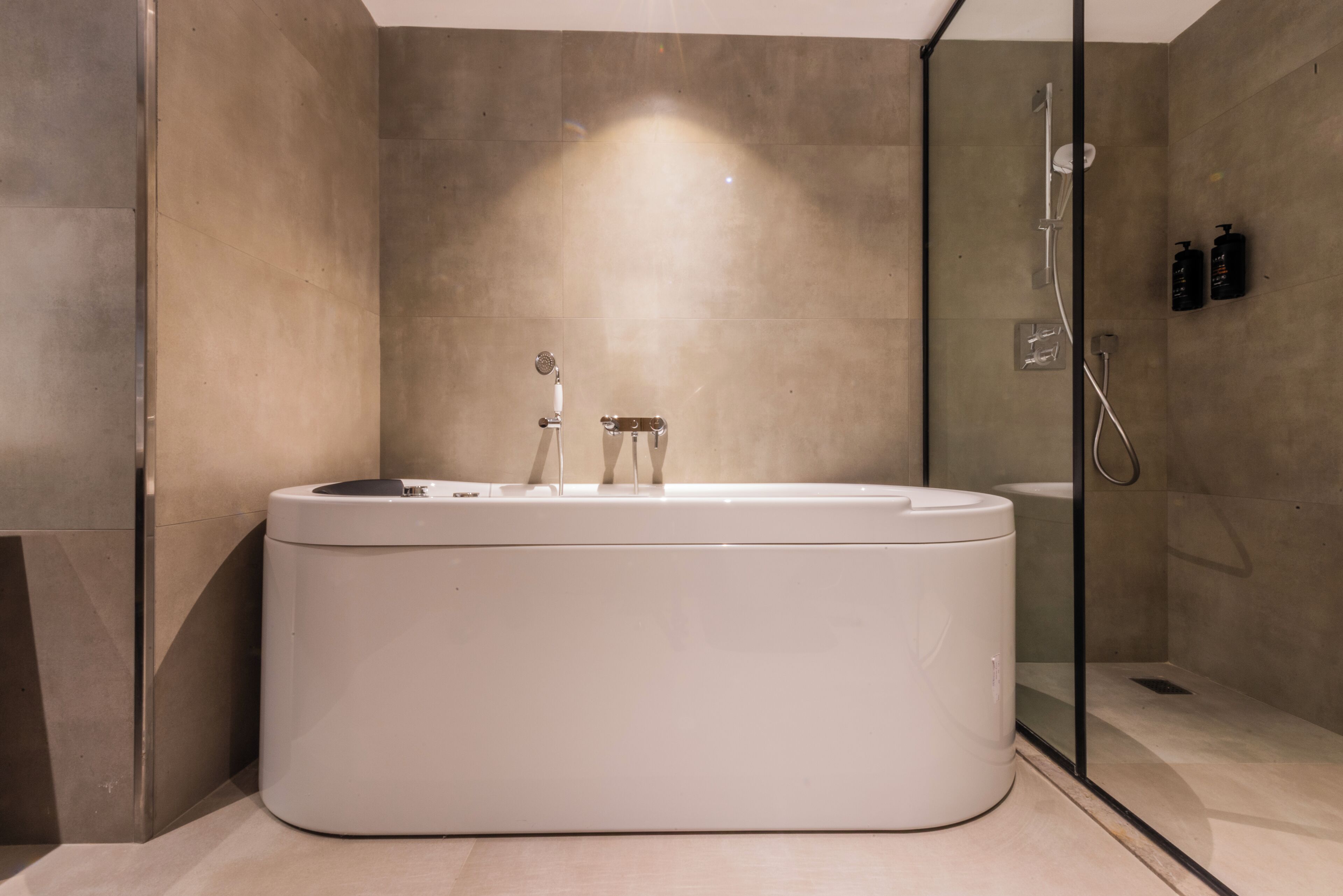 A modern bathroom with a freestanding bathtub, a glass shower enclosure, and a wall-mounted toilet.