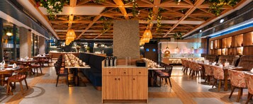 Un restaurante con una larga mesa compartida, mesas individuales y una zona de bar.