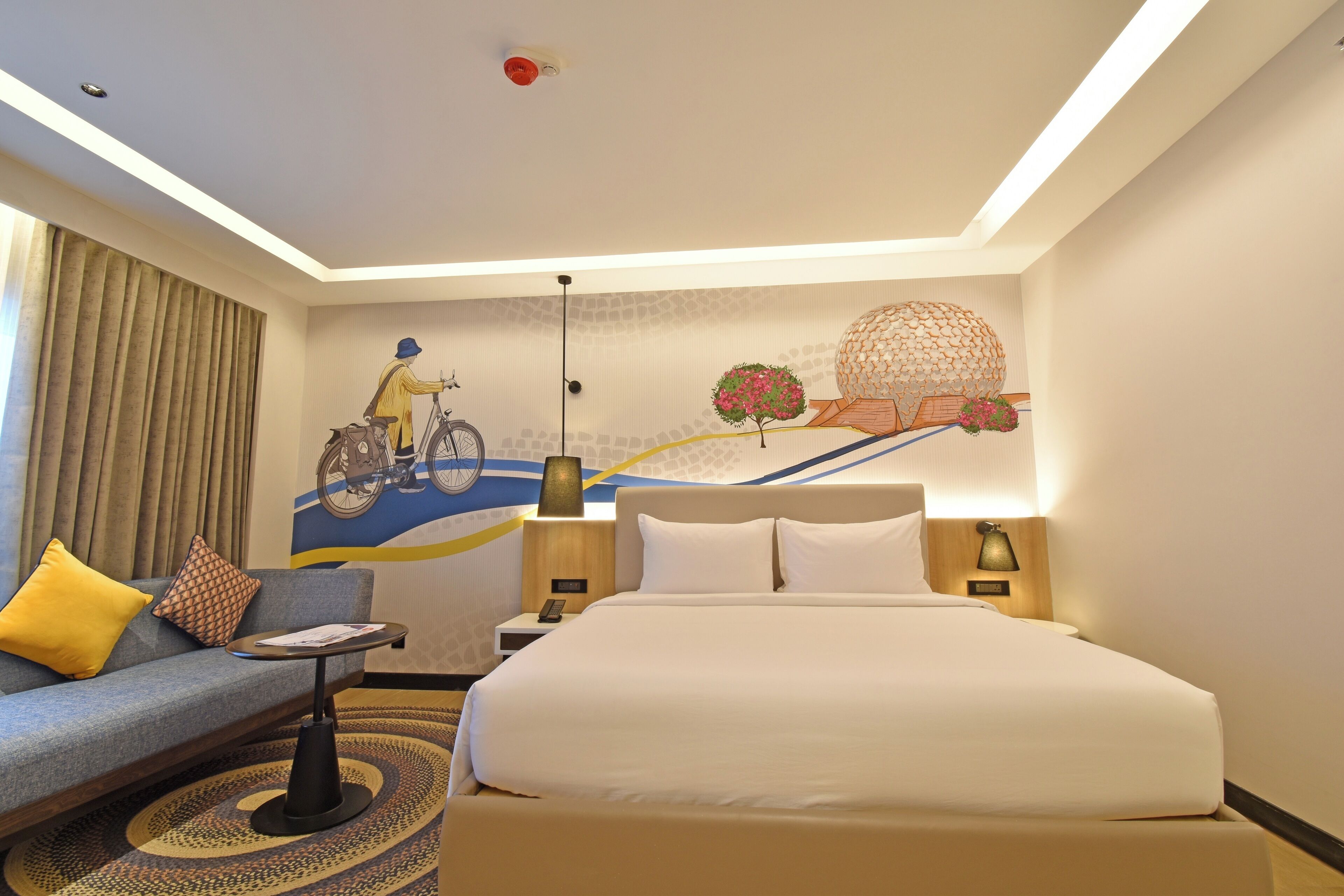 Une chambre d’hôtel avec un lit, un canapé, une petite table et une fresque murale.