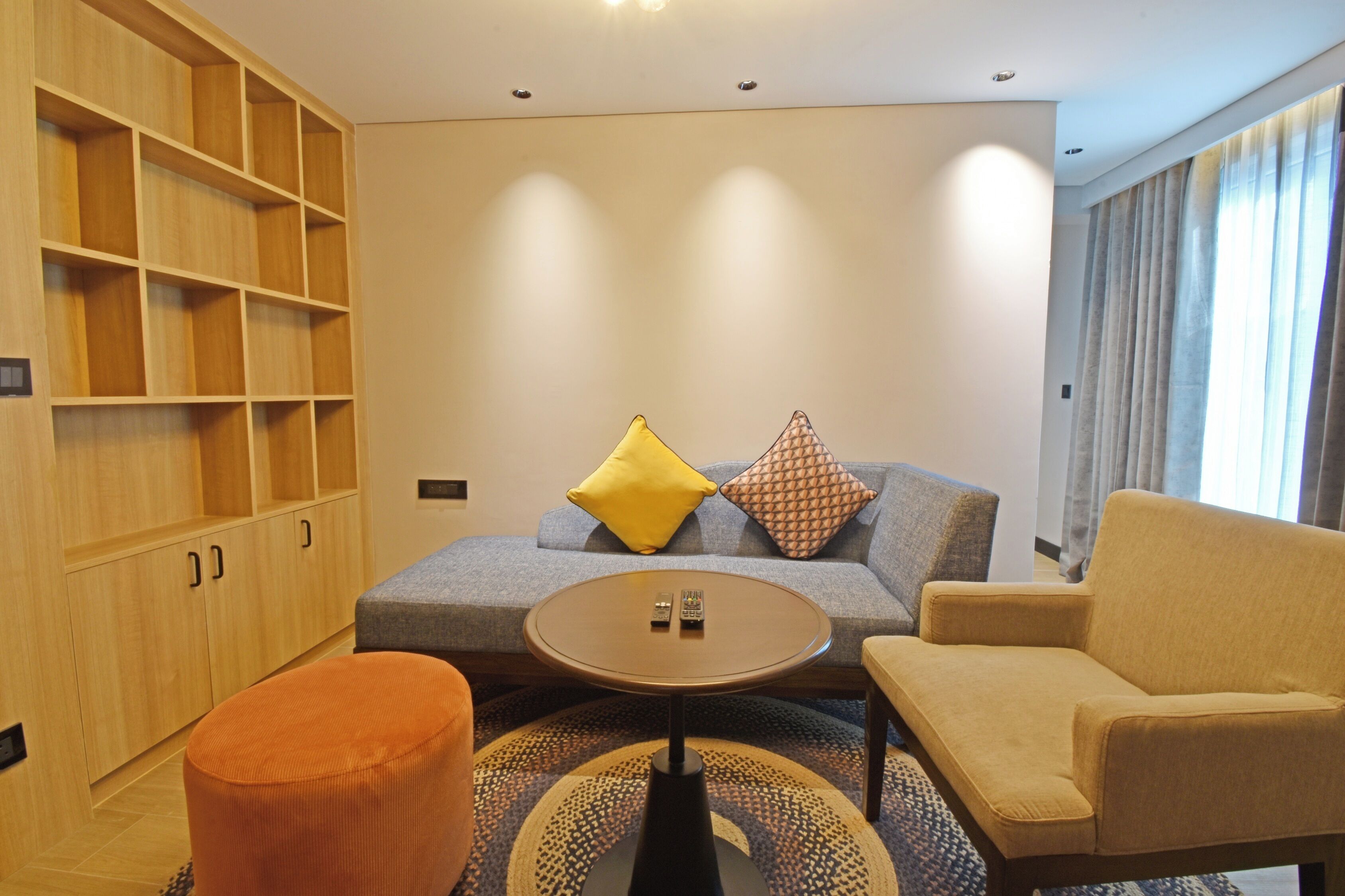 A modern living room with a sofa, armchair, ottoman, and a coffee table.