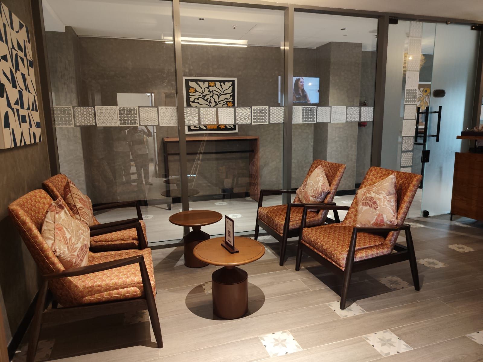 A modern interior with a glass partition, patterned wall decor, and a central round table with chairs.