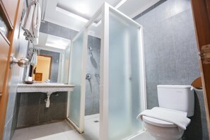 A bathroom with a glass-enclosed shower, a white toilet, and a sink with a mirror above it. - Ubud Hotel Villas Malang (Malang)