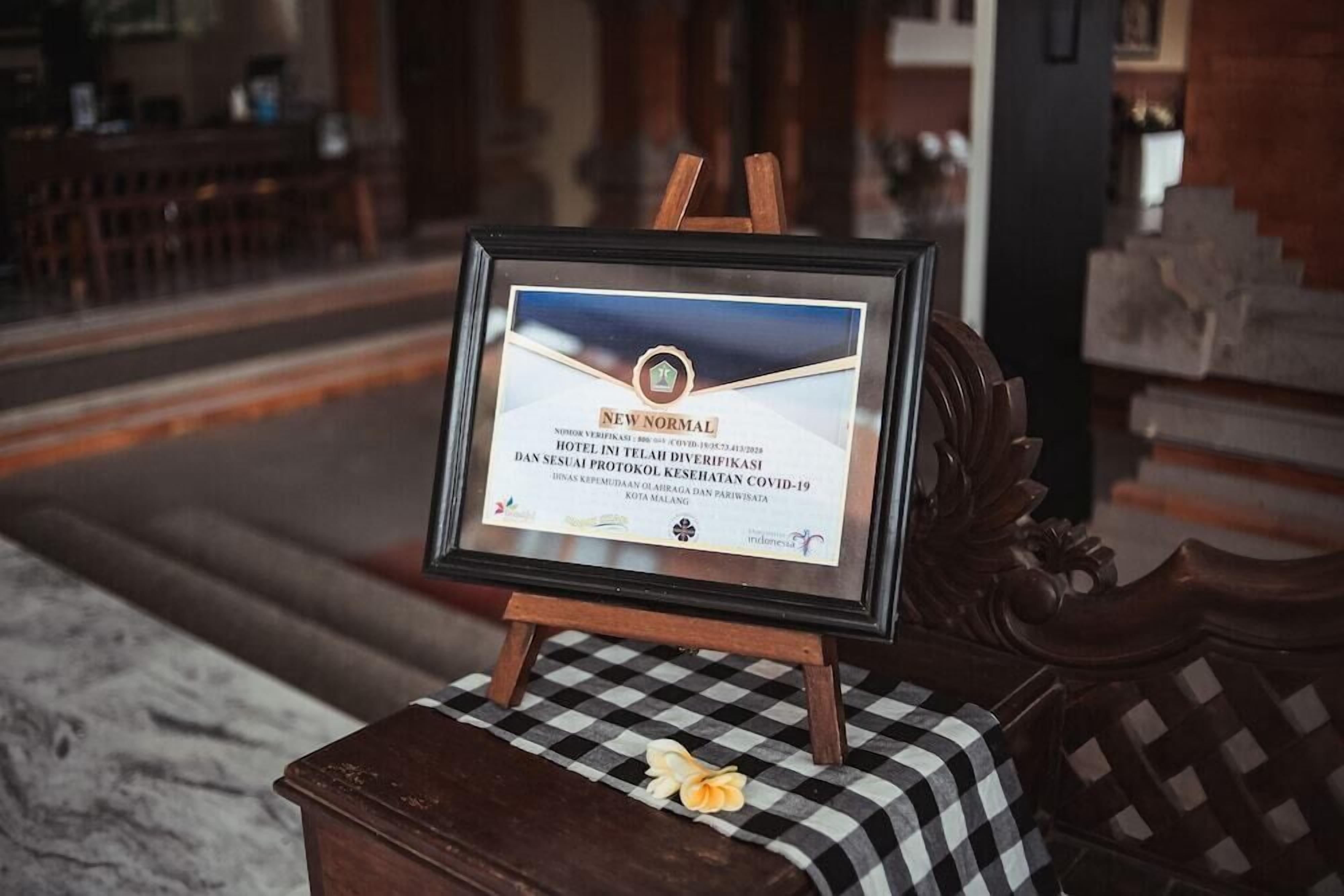A framed certificate on a wooden stand with a checkered cloth and a flower.
