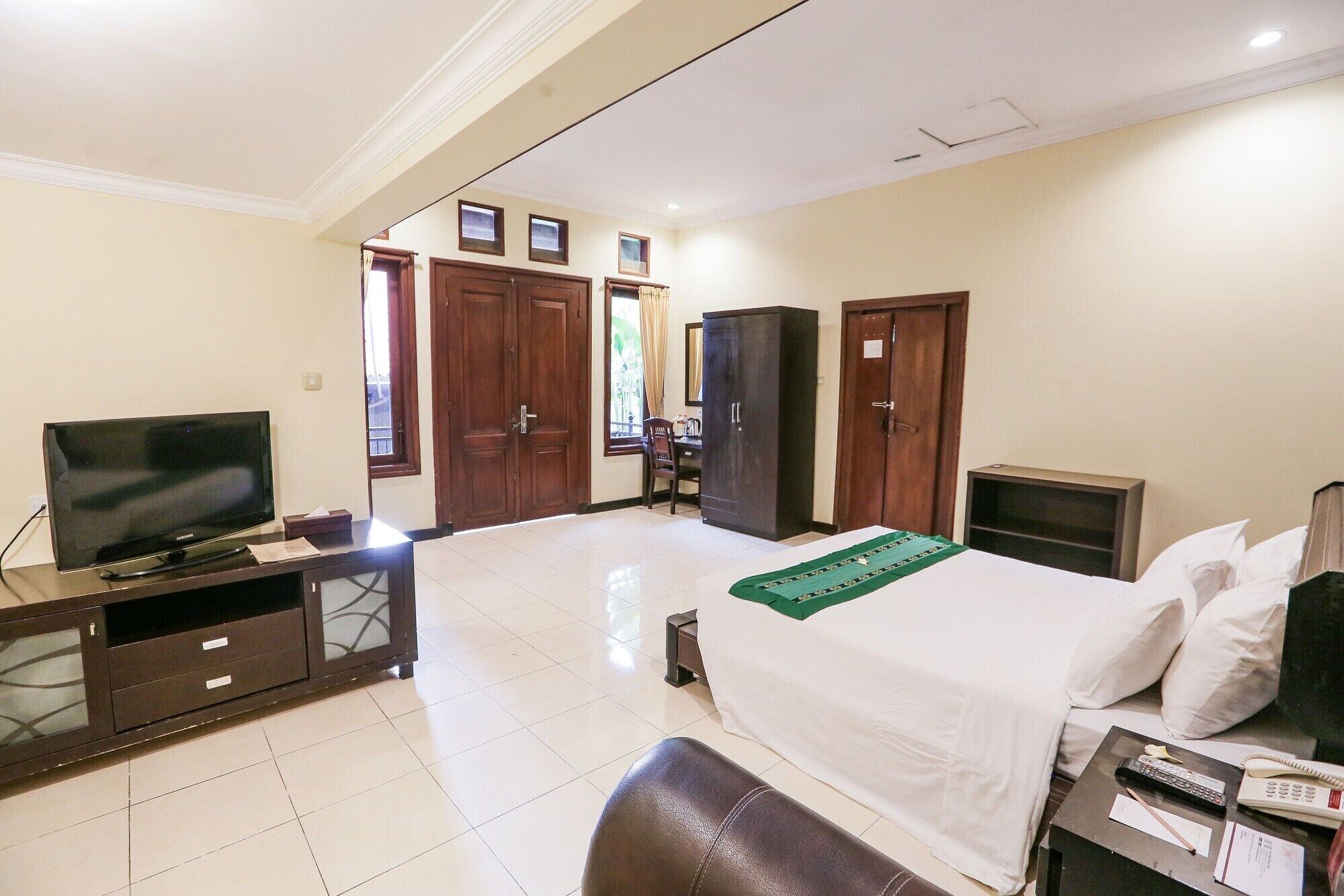 A hotel room with a bed, a desk with a computer, a television, and a wardrobe.