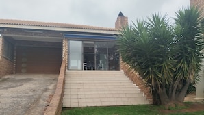Una propiedad residencial con garaje, una escalera que conduce a un patio cubierto y un pequeño jardín.