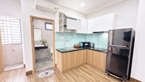 A modern kitchen with a built-in refrigerator, a sink, and wooden cabinets. - Gold Hotel & Apartment Da Nang (Da Nang)