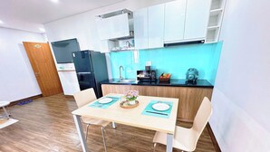 A modern kitchen with white cabinets, a black refrigerator, and a blue countertop. - Gold Hotel & Apartment Da Nang (Da Nang)