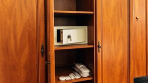 Un meuble en bois avec un coffre-fort blanc, une étagère avec un sac et quelques objets, et un crochet sur le côté droit.
