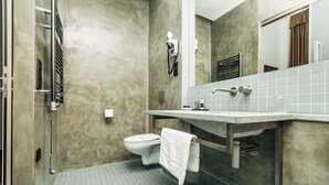 Une salle de bain équipée de toilettes, d’un porte-serviettes, d’une douche et d’un miroir.