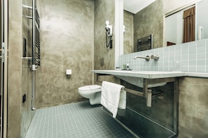 Une salle de bain équipée de toilettes, d’un porte-serviettes, d’une douche et d’un miroir.