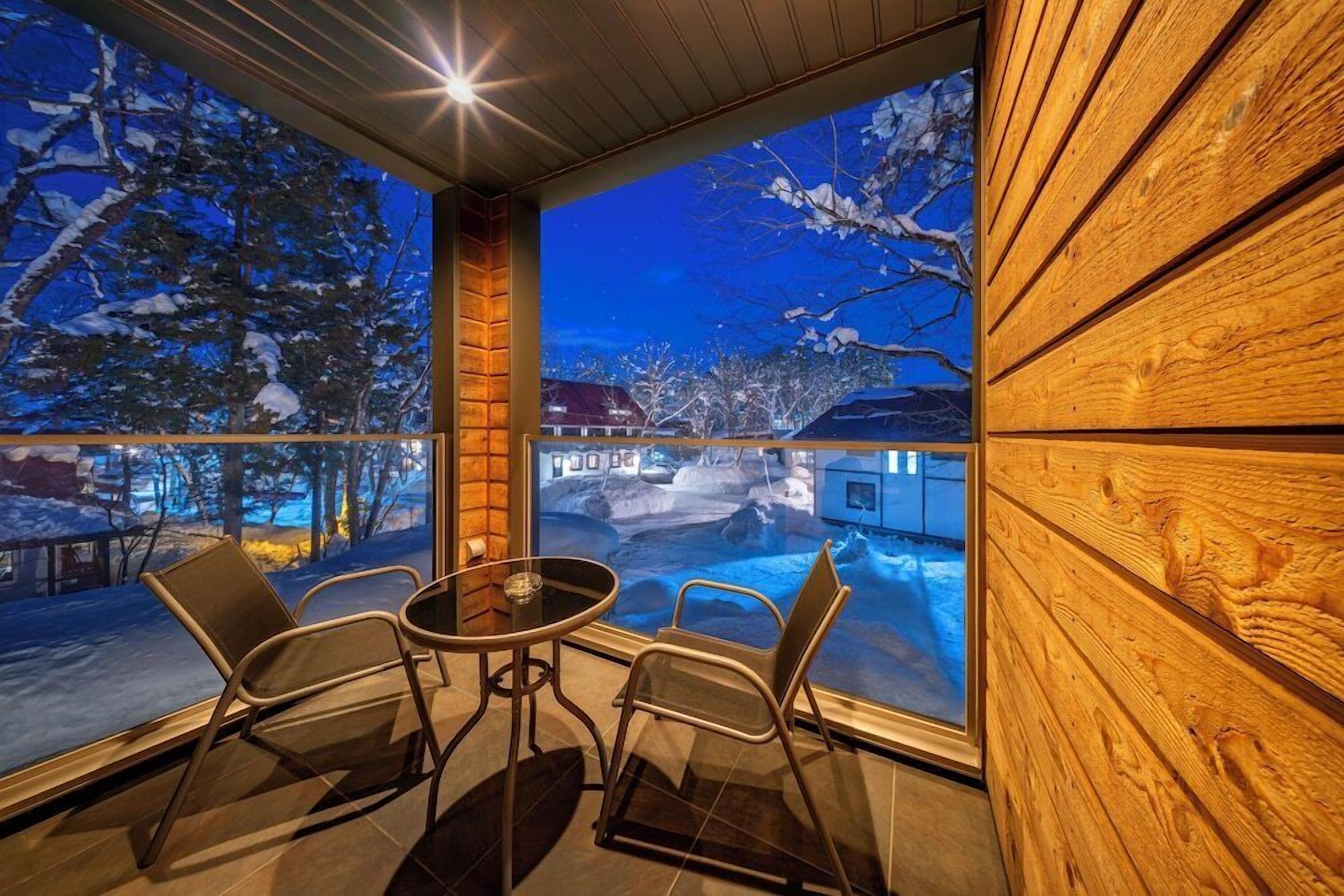 A cozy room with a large window overlooking a snowy landscape and a wooden interior.