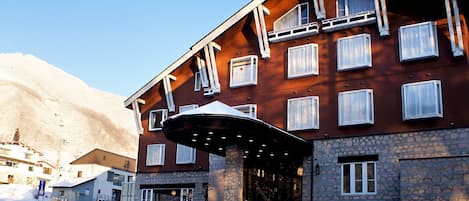 A multi-story building with a stone facade and a large entrance canopy.