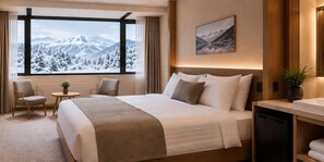 Une chambre d’hôtel avec un grand lit, deux fauteuils, une petite table et une fenêtre donnant sur la montagne.