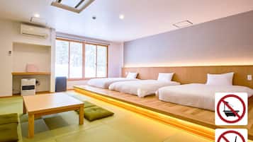 A modern hotel room with a large bed, a small desk, and a window. There are signs indicating no smoking and no outside food.