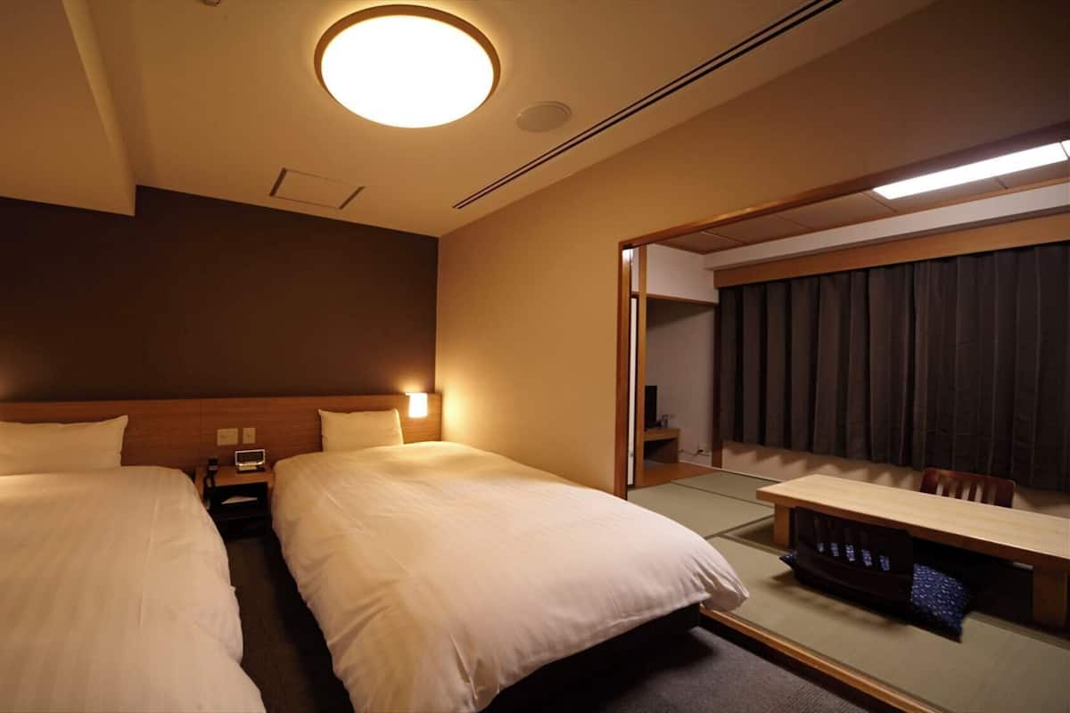 A hotel room with two beds, bedside tables, a mirror, a desk, and a ceiling light.