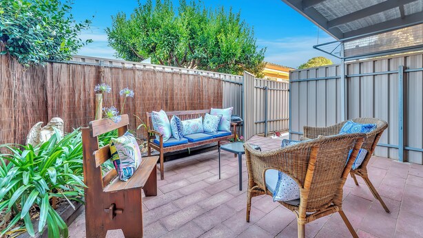 An outdoor patio with a wooden bench, wicker chairs, and a sofa with blue cushions. - Colour Pop Cottage - A vibrant courtyard retreat perfect for long stays (Payneham)