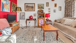 A living room with a TV, sofa, coffee table, and artwork on the walls. - Colour Pop Cottage - A vibrant courtyard retreat perfect for long stays (Payneham)
