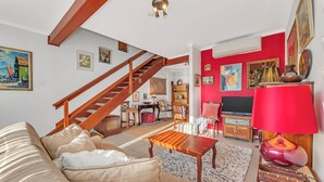 A living room with a wooden staircase, a sofa, a coffee table, and a TV. - Colour Pop Cottage - A vibrant courtyard retreat perfect for long stays (Payneham)