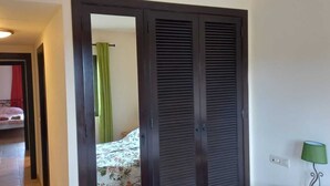 Ein Zimmer mit einem Bett, einem grünen Vorhang, einer schwarzen Tür und einer grünen Lampe.