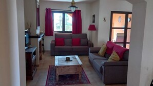 Ein Wohnzimmer mit einer Sofagarnitur, einem Couchtisch und einem Fernseher.