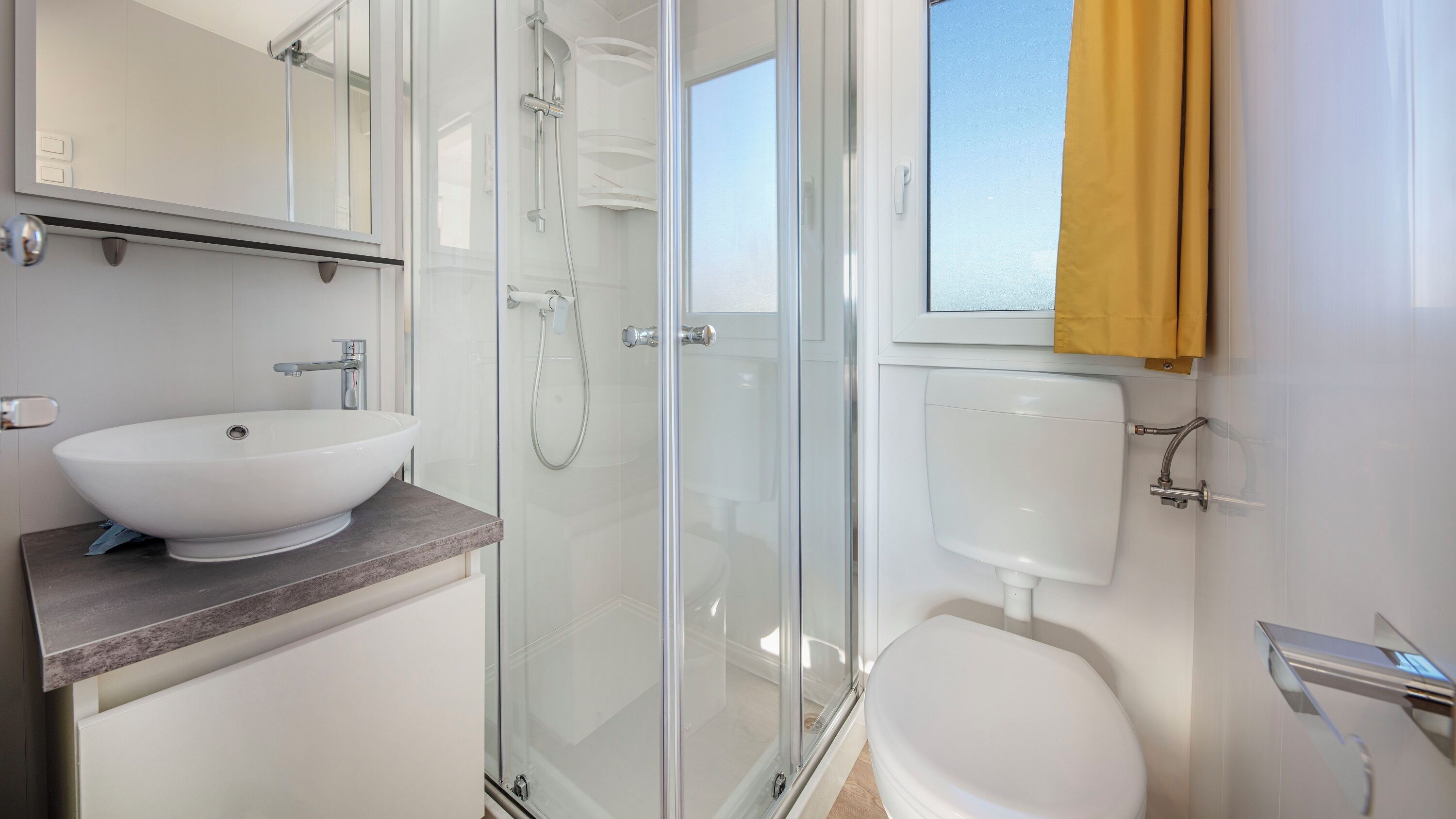 A modern bathroom with a glass-enclosed shower, a white sink, and a toilet.