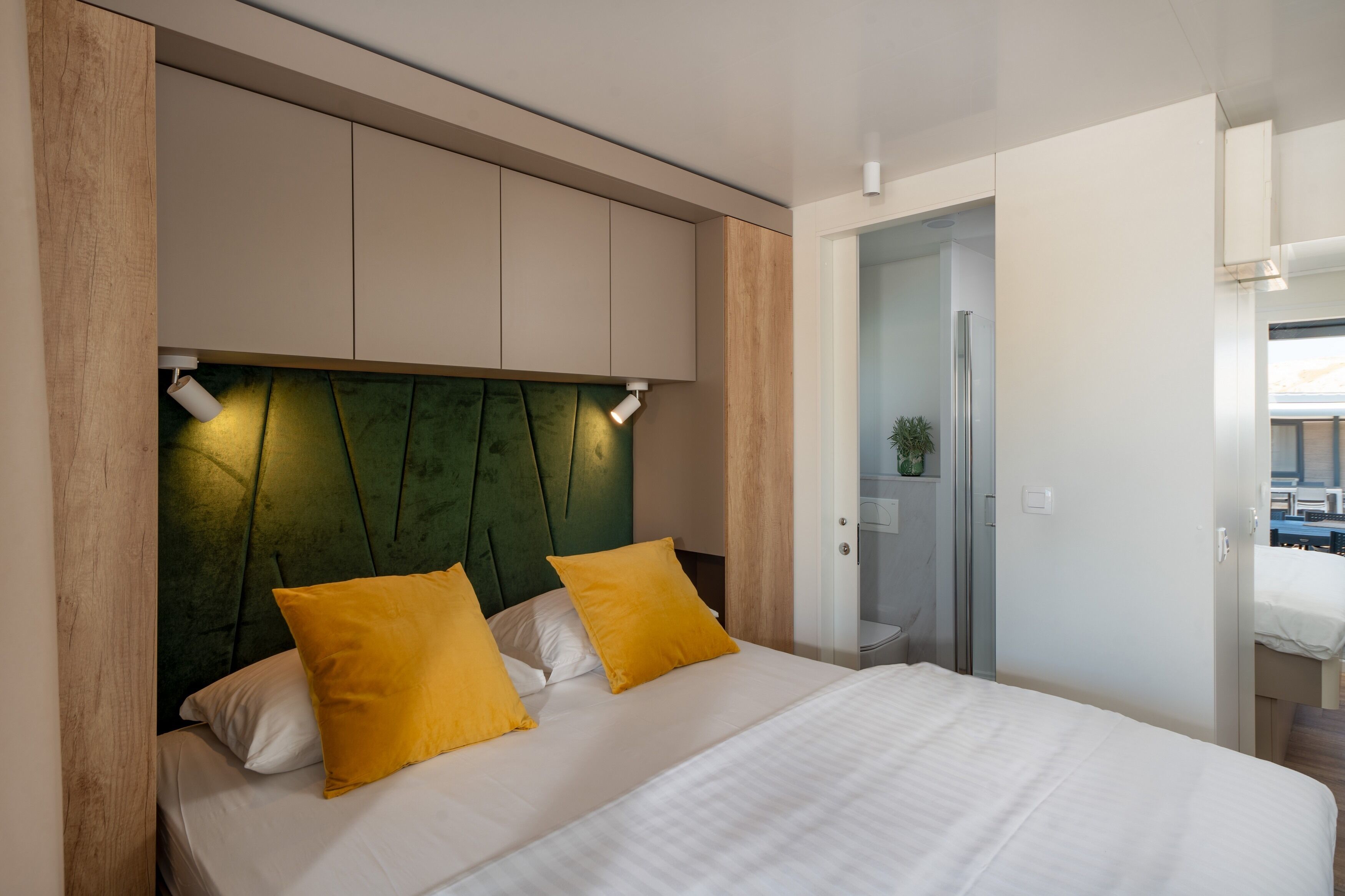 Habitació d'hotel moderna amb llit, capçalera tapissada de verd i paret decorativa de fusta.