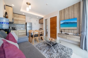 A modern living room with a sofa, a coffee table, and a TV mounted on the wall. - Tropical Poo View 1 BR Apt Babylon M206 (Rawai)