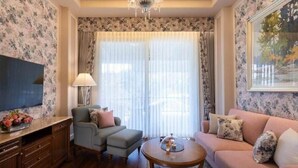 A living room with a sofa, armchair, and coffee table, a TV, and a window with curtains. - Welcomhotel by ITC Hotels, The Savoy, Mussoorie (Dehradun)