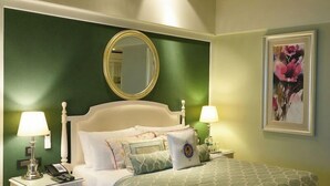 A neatly arranged bedroom with a bed, two bedside tables with lamps, a round mirror, and a framed picture on the wall. - Welcomhotel by ITC Hotels, The Savoy, Mussoorie (Dehradun)